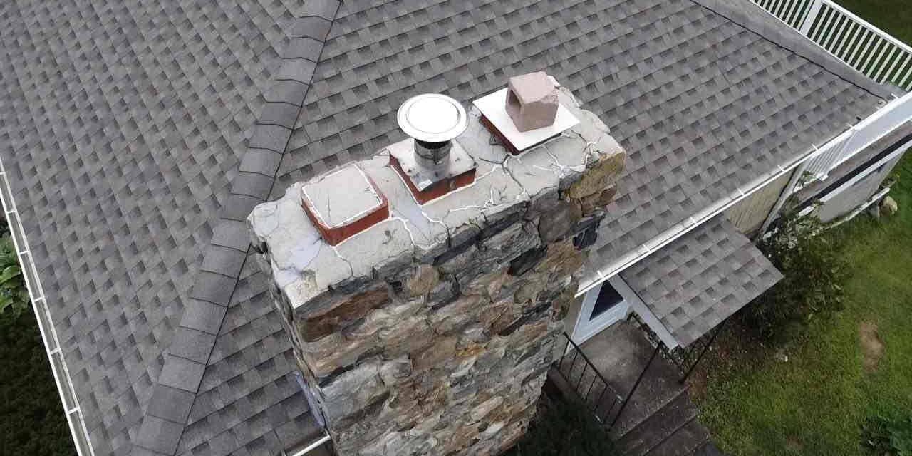 colebrook-service-titan-job-70595770-stone-chimney Stone chimney with visible crown deterioration documented during an inspection in Colebrook, CT.