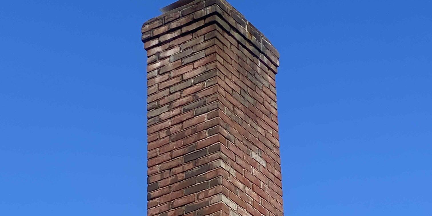 Chimney liner and cap – Hartland, CT Tall brick chimney with a new stainless-steel liner and cap in Hartland, CT.